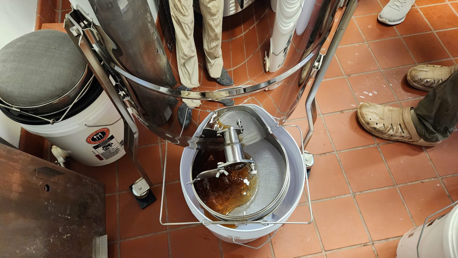 Honey straining through a mesh filter into a bucket during extraction